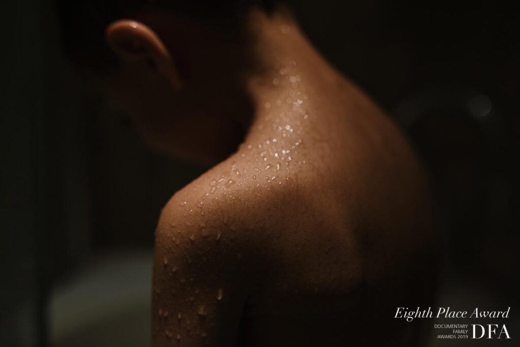 Water droplets glistening on a child's bare shoulder in dramatic low light, with an Eighth Place DFA award mark.