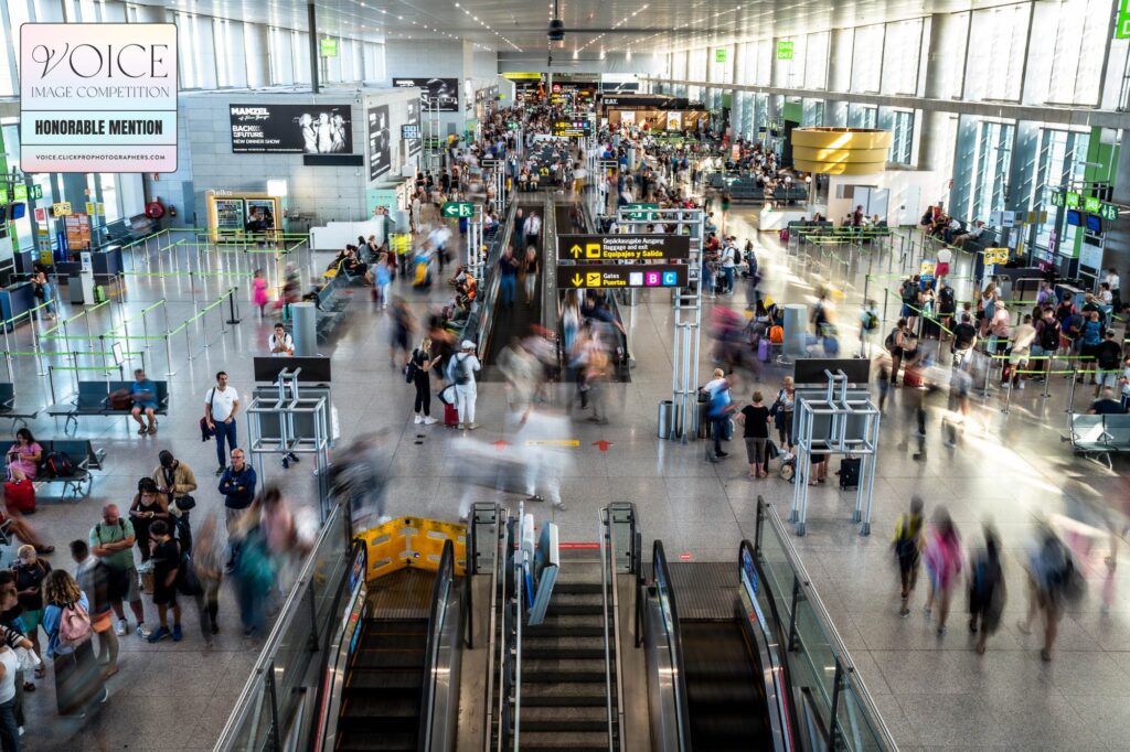 Overview of a busy Malaga airport with a long exposure showing the blur of people rushing around amongst those standing still.