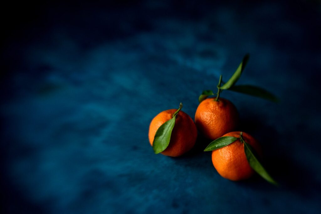 3 orange clementines on a dark blue background