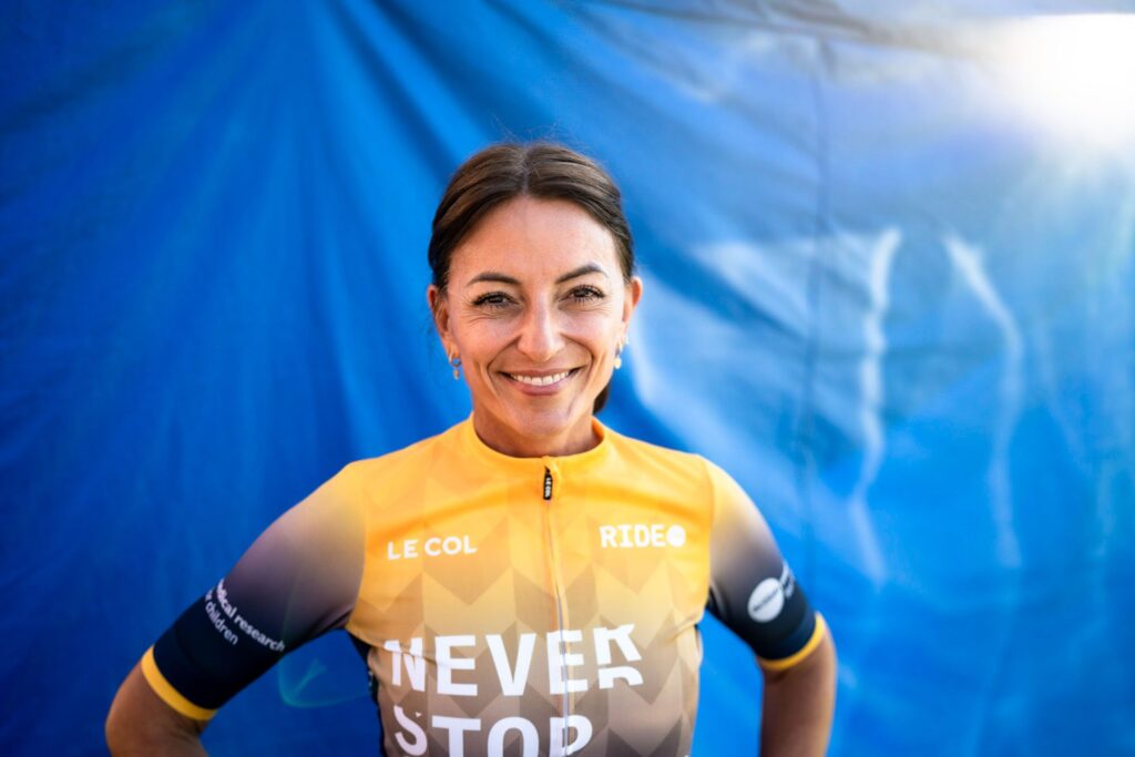 Davina McCall posing in her cycling gear against a blue backdrop at a charity fundraising event in East Sussex 