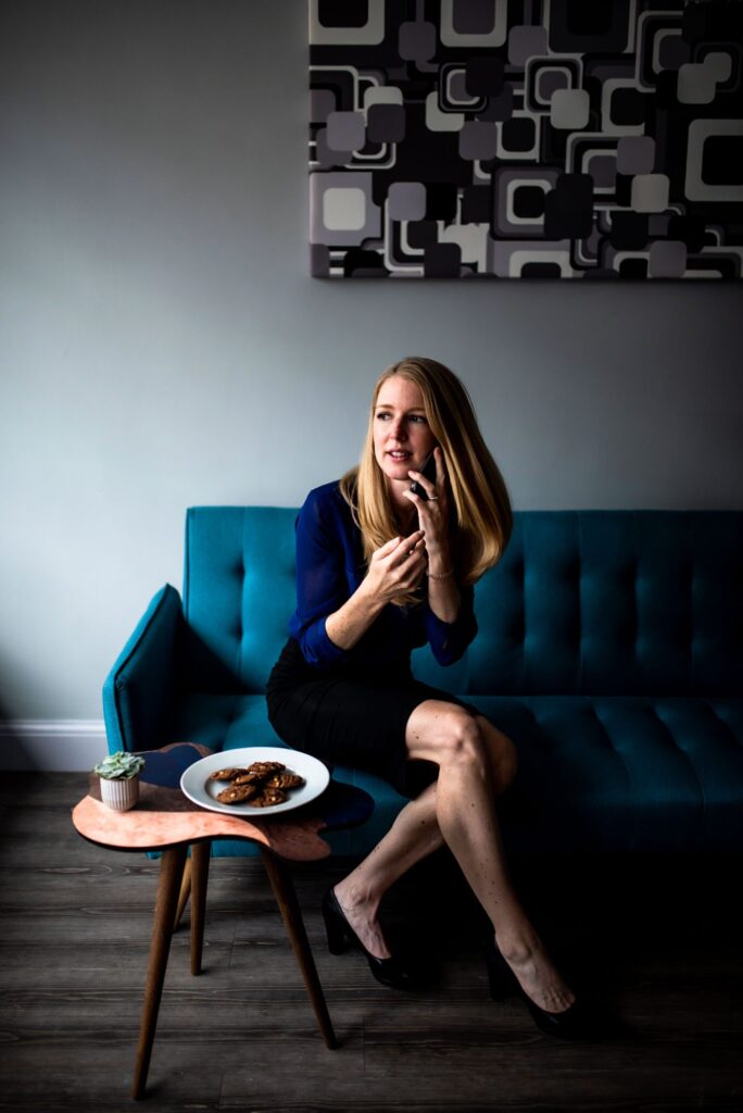 A blonde woman on a blue sofa, on the phone in an accountant's office