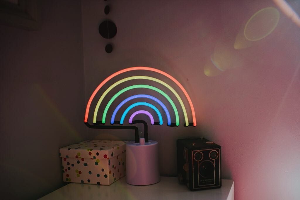 A neon rainbow light with a sun flare coming from the side