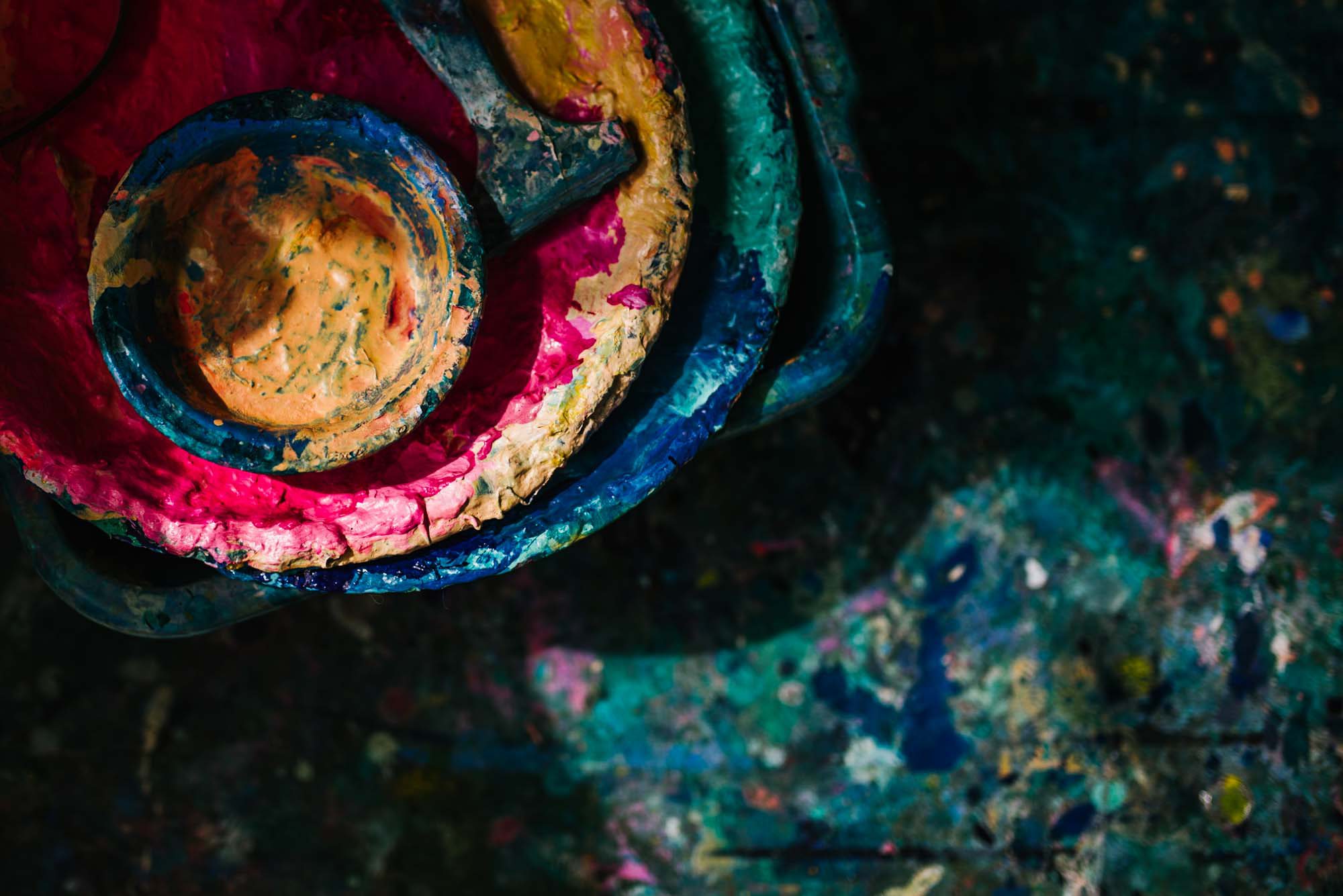 Abstract details of an artist's colourful floor covered in paint and palettes.