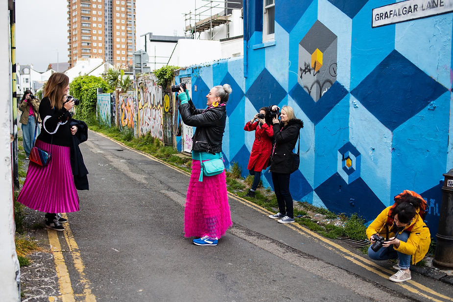 Multiple female photographers capturing each other on a colourful graffiti street in Brighton