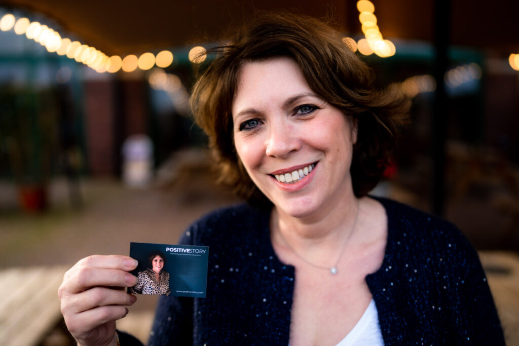 Jane Griffin, a white woman with short brown hair, holding her business card showing her headshot printed